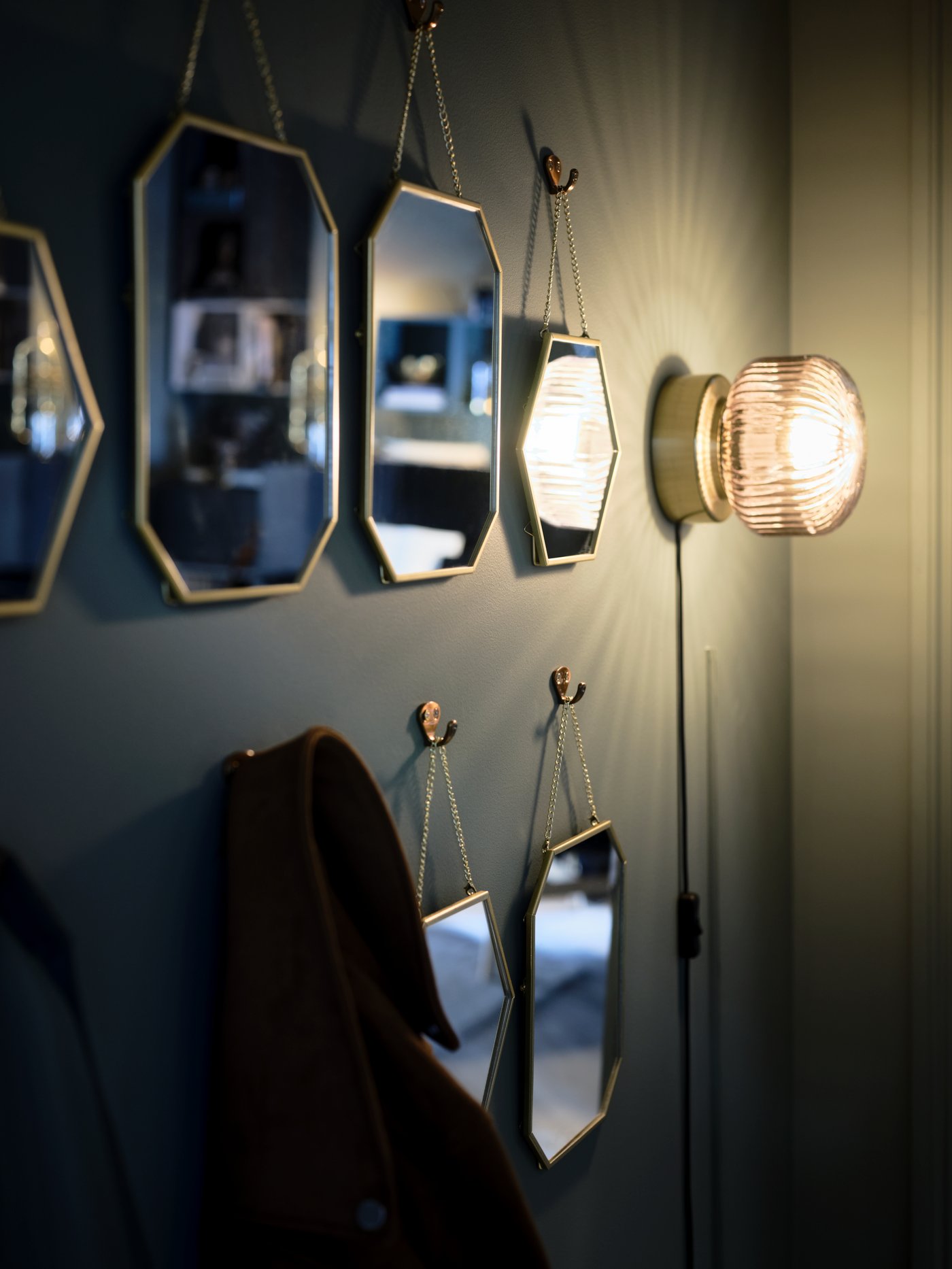 SOLKLINT wall lamp on a wall in the hallway next to a few mirrors hanging on the wall.