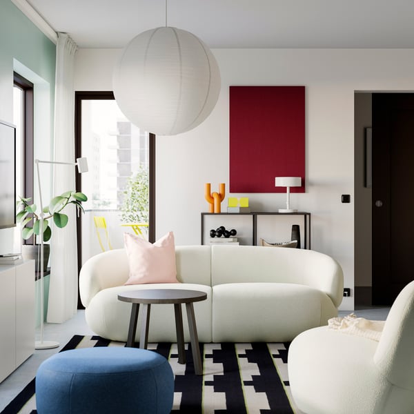 Un sofá LILLESÄTER de 3 puestos color blanco con un cojín adicional sobre él en una sala con muebles modernos.