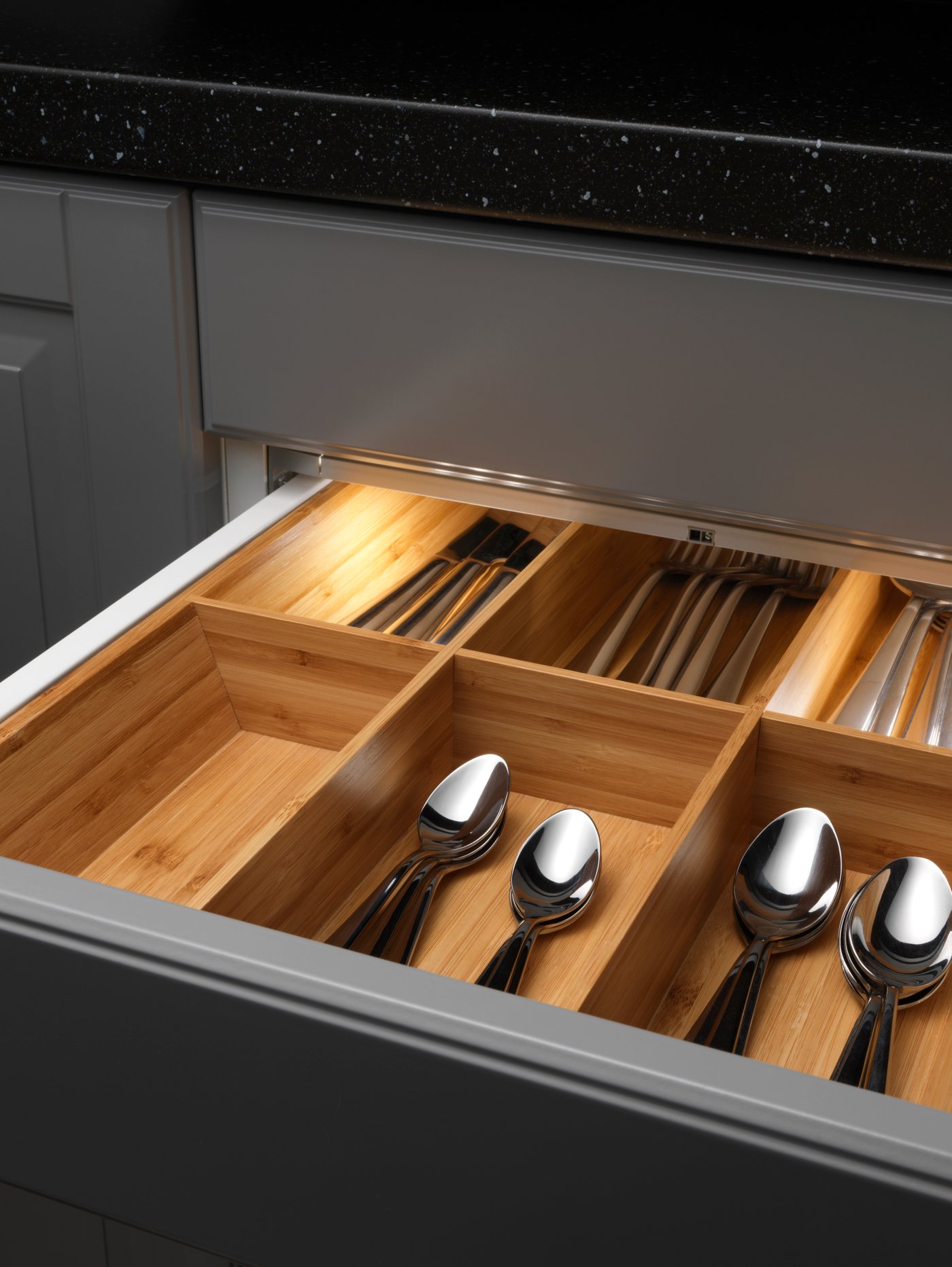 An open drawer in a kitchen with brown SINARP fronts, showing plates and bowls on an UPPDATERA pegboard drawer organiser.