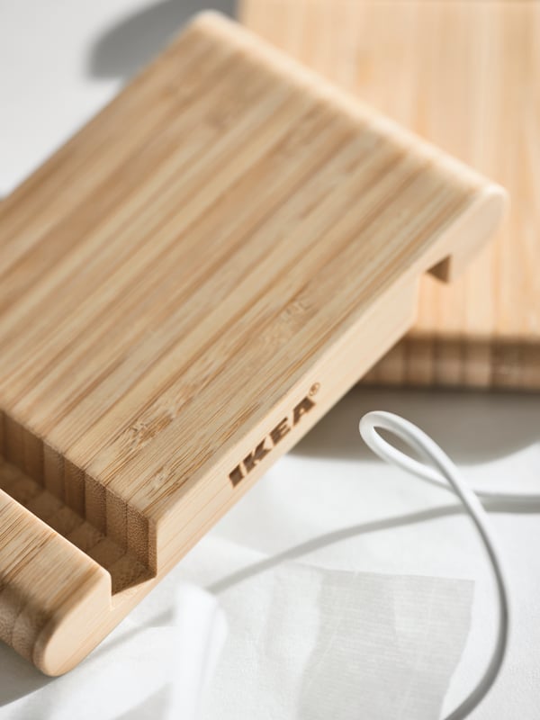 Two bamboo BERGENES holders for mobile phone/tablet and a white wire on a brightly lit white surface.