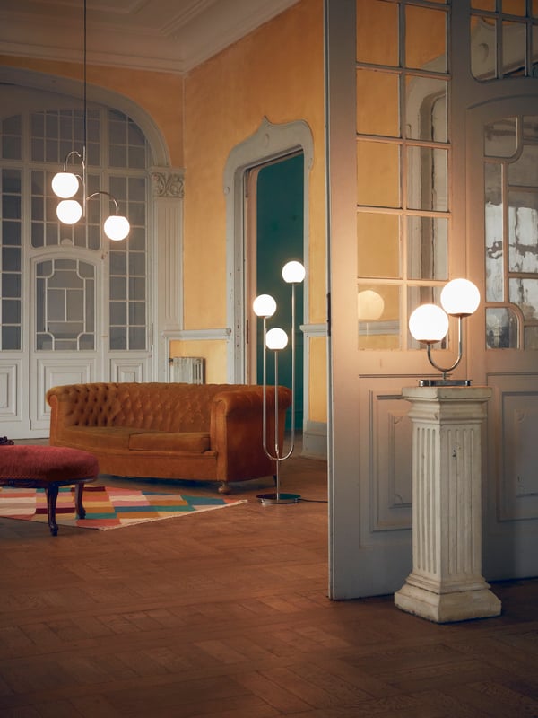 Une grande pièce dans laquelle se trouvent trois lampes SIMRISHAMN : une lampe de table, un lampadaire et une suspension, le globe allumé.