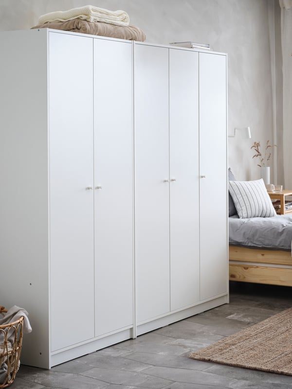 Two white KLEPPSTAD wardrobes – one 2-door and one 3-door side by side next to a pine UTÅKER stackable bed in a white room.