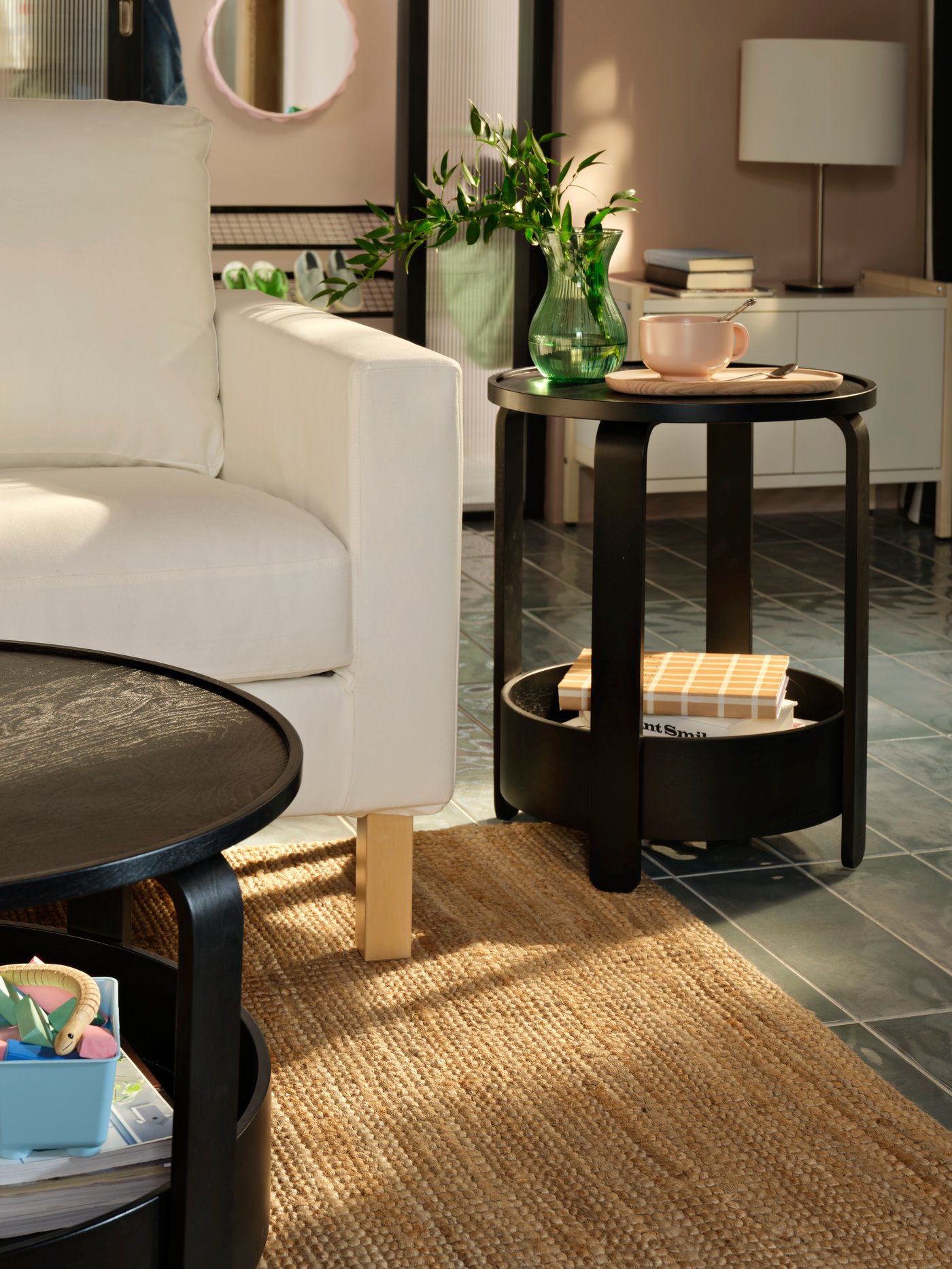 A light living room with a black BORGEBY side table and coffee table, both placed near a white SALTSJÖBADEN two-seat sofa.