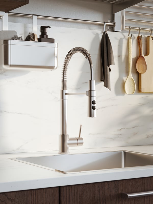 A VIMMERN mixer tap and handspray on a white countertop, under a stainless steel KUNGSFORS rail with hooks and a container.