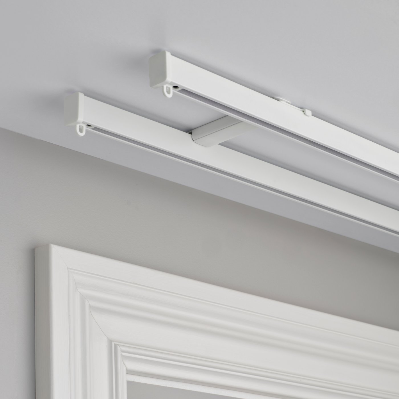 A white VIDGA ceiling bracket for 2 curtain rails