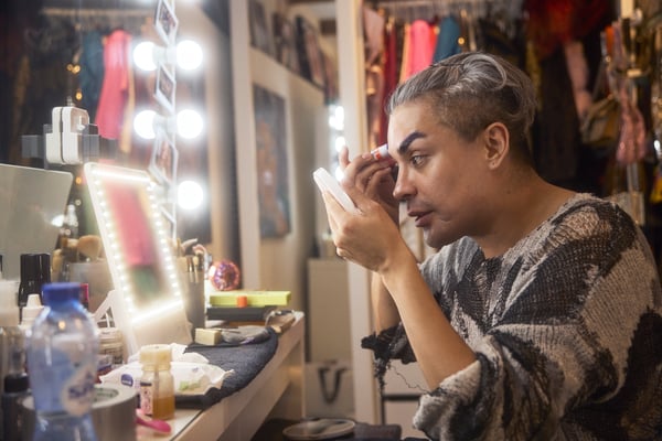 Envy in her dressing room putting on make up while looking into her vanity mirror.