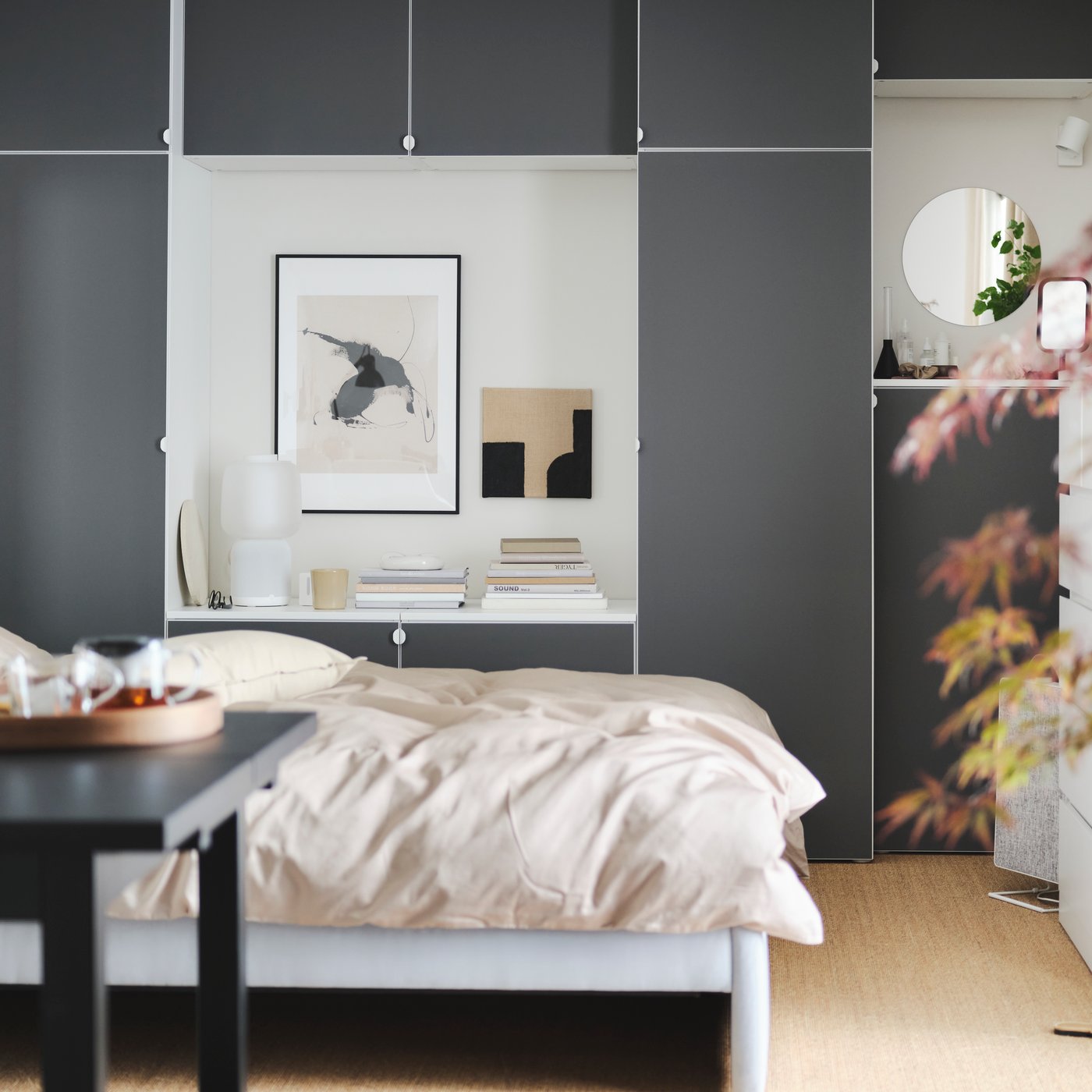A calm bedroom with a grey GLADSTAD bed, a wooden desk, a dynamic grey wardrobe and round lamps hanging from the ceiling.