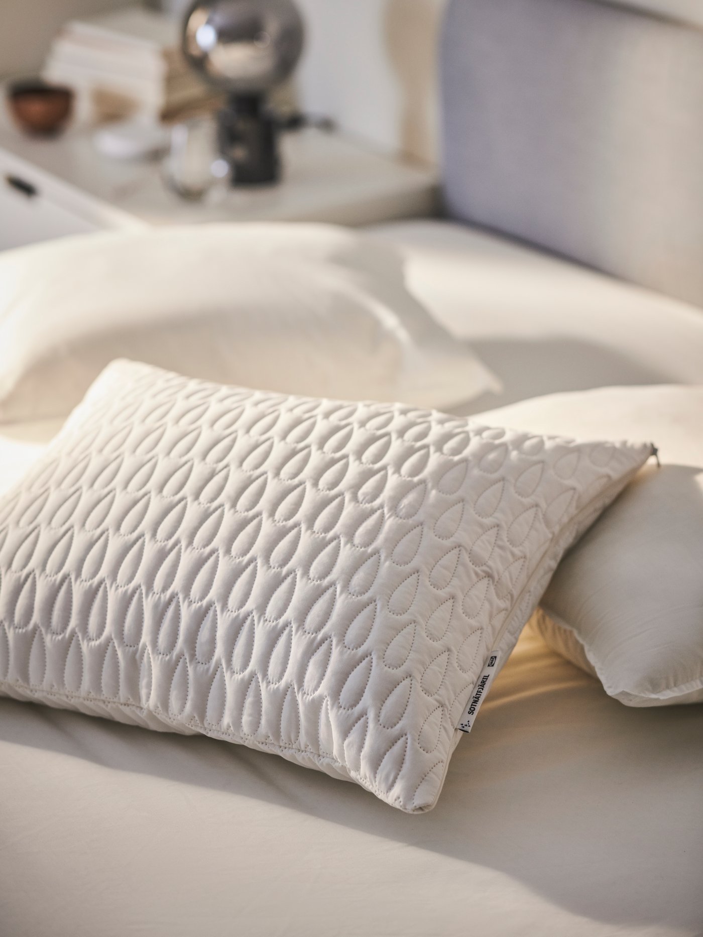 Se ve una cama sin plumón, con una almohada con protector de almohada SOTNÄTFJÄRIL encima.