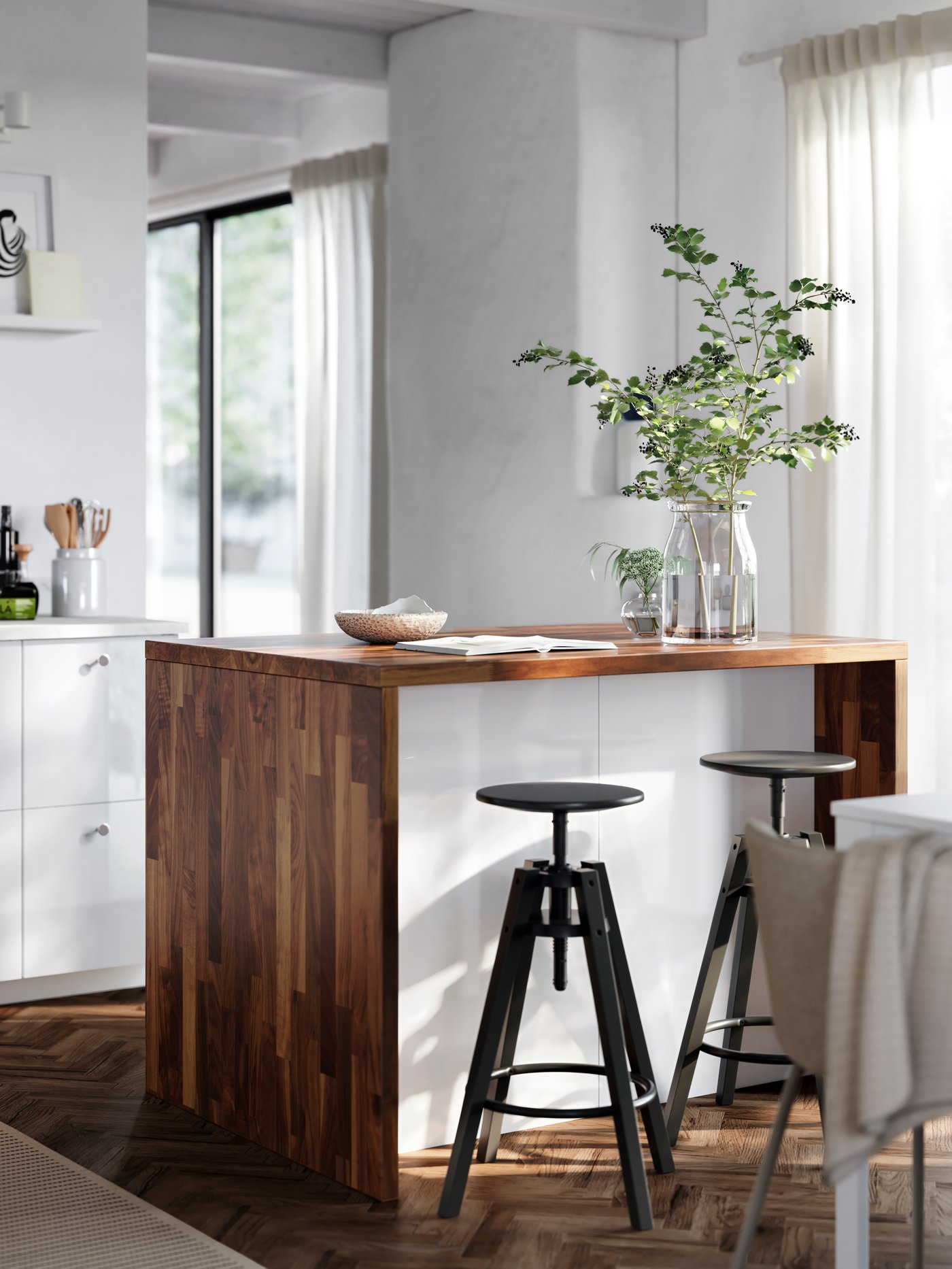 A kitchen island with worktop and cover panels in dark walnut effect is placed in a kitchen with high gloss RINGHULT fronts.