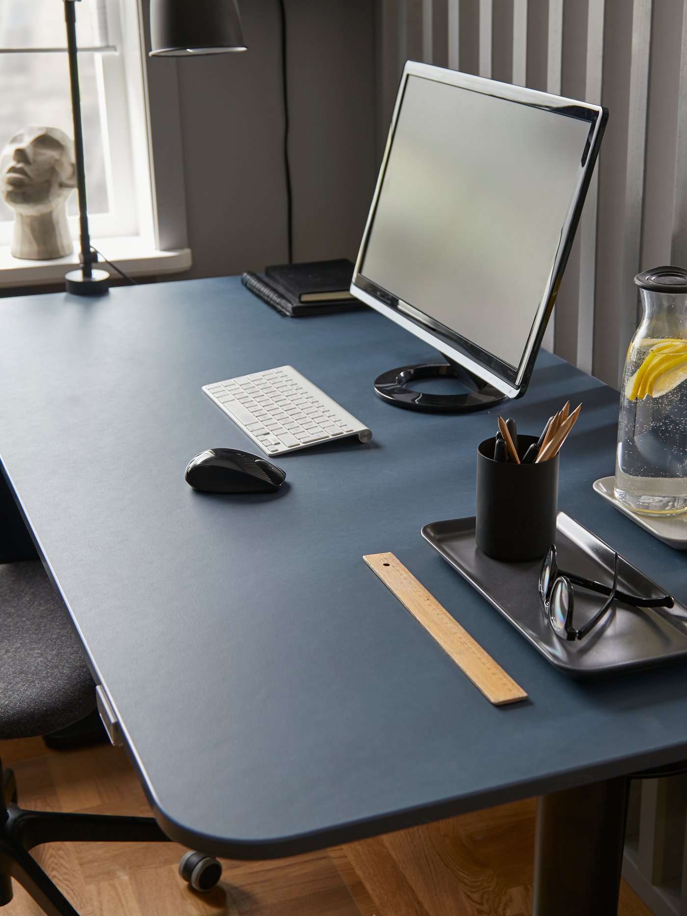 Una scrivania per seduta attiva BEKANT linoleum blu/nero con uno schermo, una bottiglia d’acqua e altri articoli da lavoro - IKEA