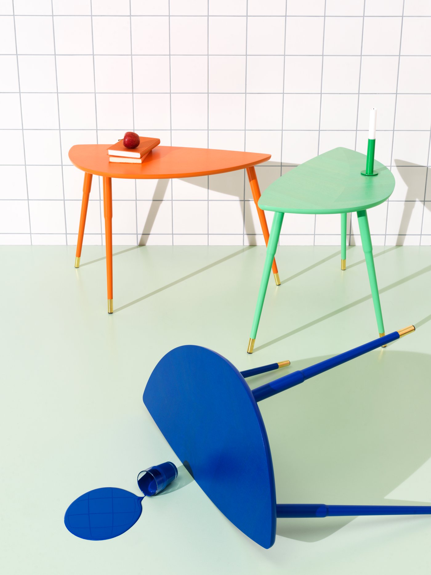 A blue LÖVBACKEN side table is tipped over spilling a glass of blue paint on the floor. Behind are two other LÖVBACKEN.