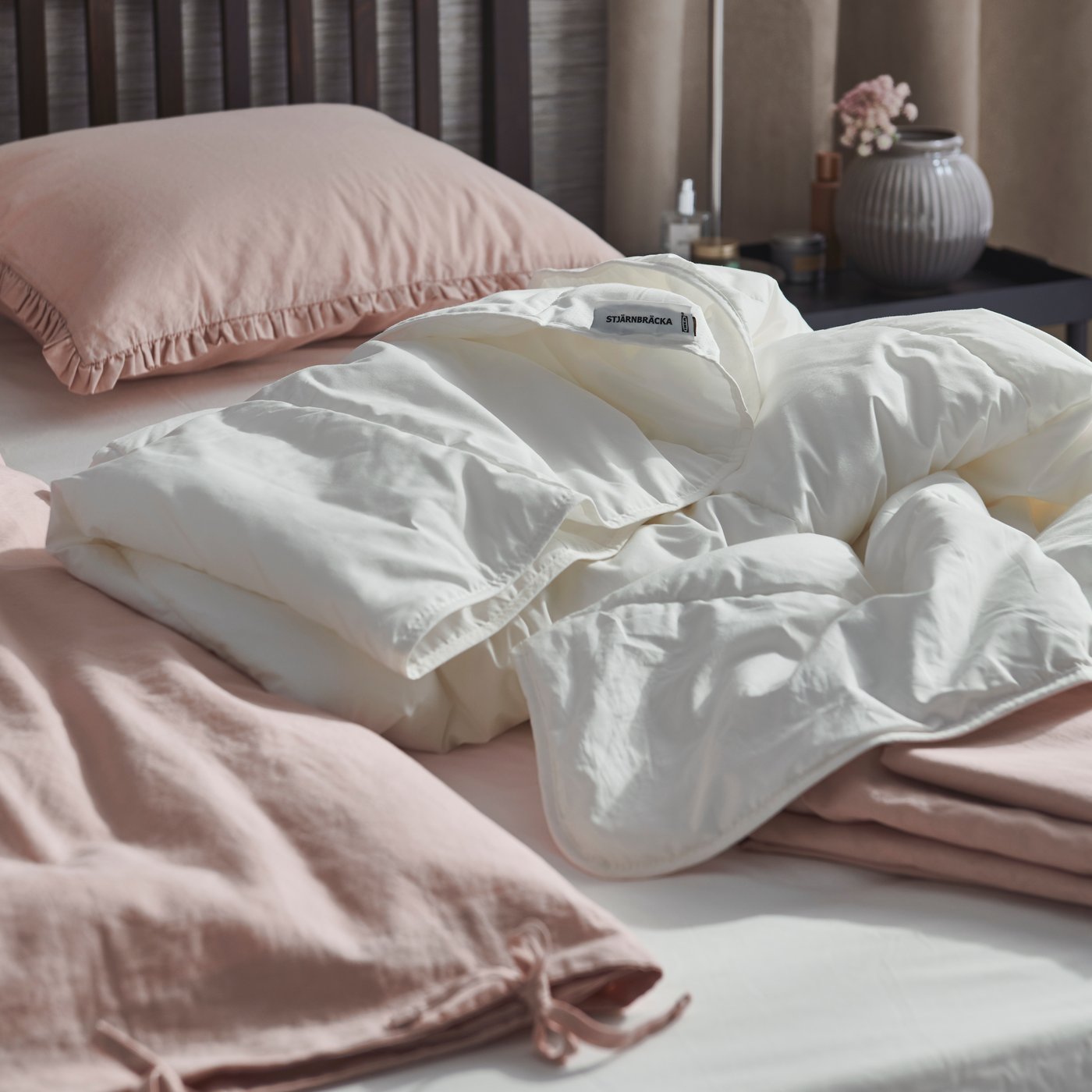 Rosa und weiße Bettwäsche auf einem Bett liegend.