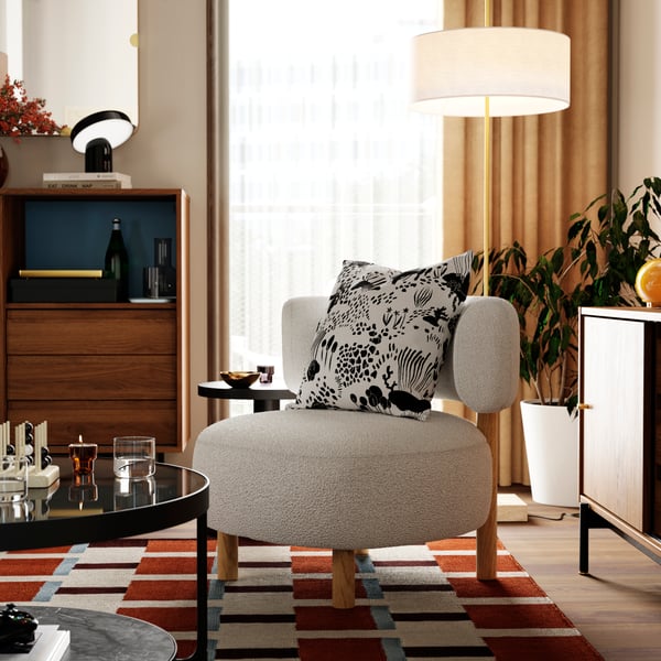 Coussin revêtu d’une housse de coussin STOCKHOLM 2025 sur un fauteuil STOCKHOLM 2025, à côté d’une table basse FRÖTORP.