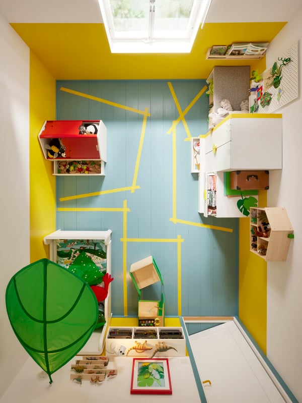 Vista de la sala infantil desde arriba, con zonas para diferentes actividades y funciones marcadas en el suelo.