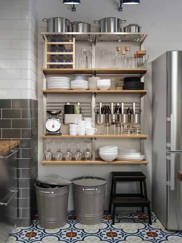 A large wall-mounted storage solution with wooden shelves and rails holding tableware, cookware and utensils.