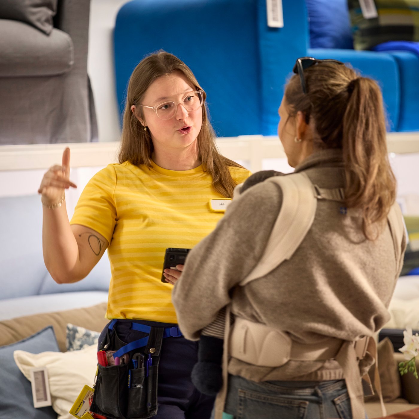 Collaboratrice IKEA parlant à une cliente dans le département Canapés d’un magasin.