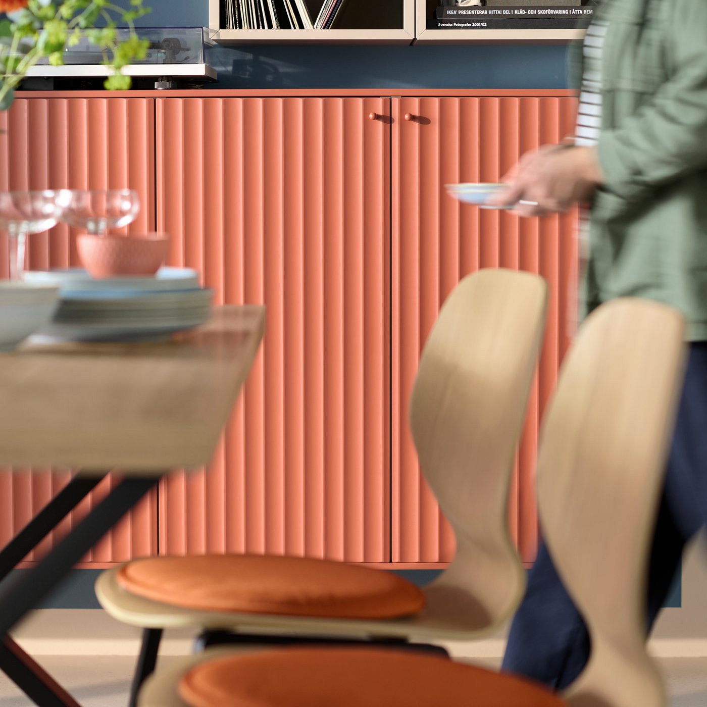 Gros plan sur une chaise SKÅLSTA avec une coque en chêne plaqué dans une salle à manger, avec des armoires aux portes décoratives TERRSJÖ.