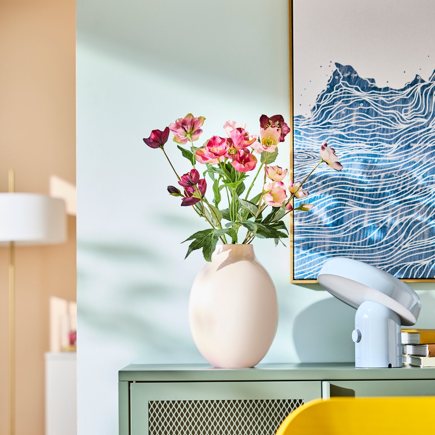 A BLODBJÖRK vase in beige with a colorful bouquet of flowers on a green sideboard

