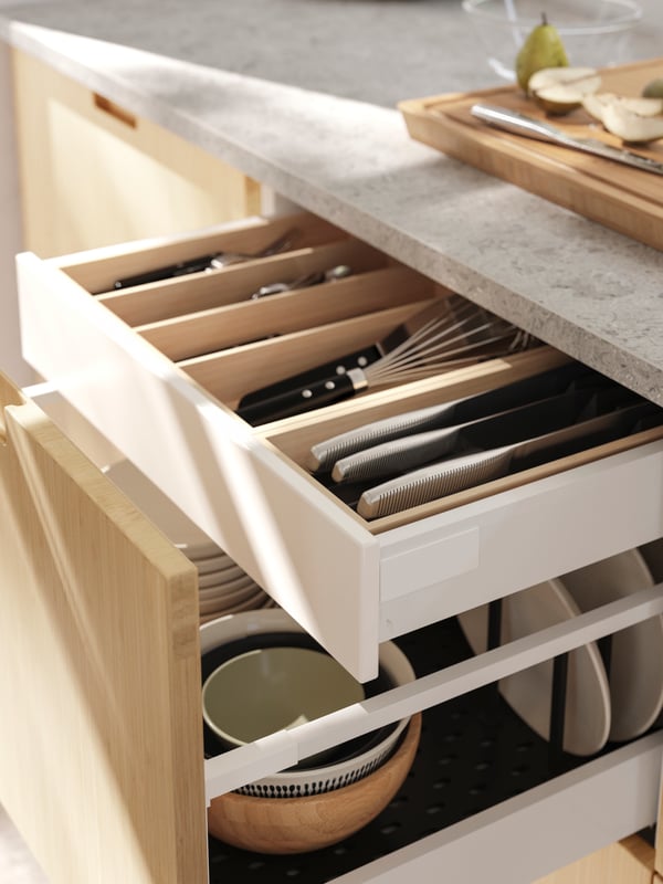 A kitchen drawer, with a FRÖJERED front, is open, revealing UPPDATERA drawer inserts with utensils and three IKEA 365+ knives.