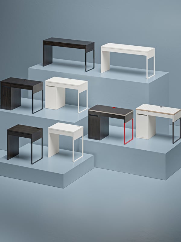 A multlevel podium displaying several MICKE desks and drawer units in different combinations of size, colour and setup.