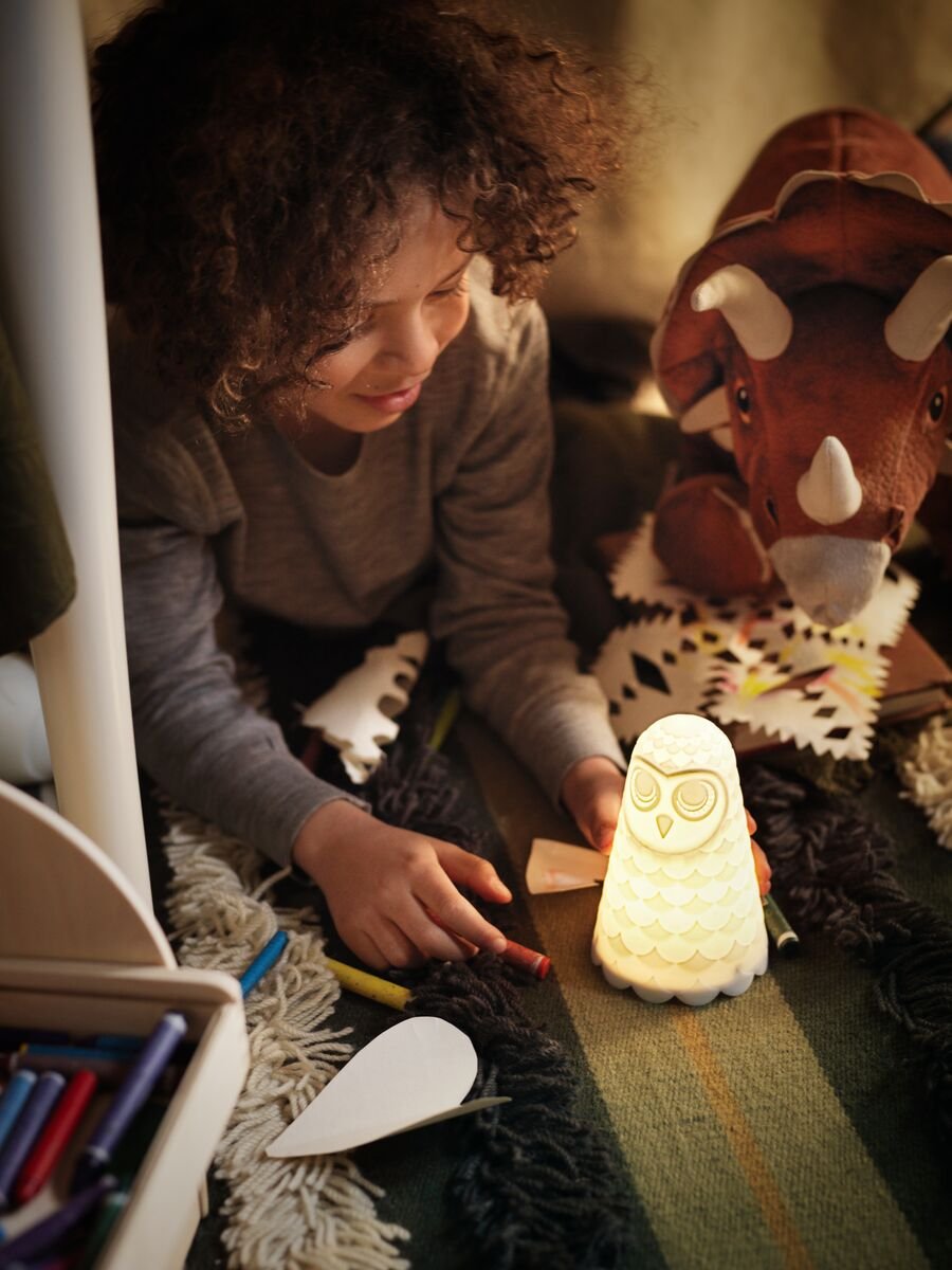 Un niño jugando debajo de la mesa con una lámpara SOLBO encendida.