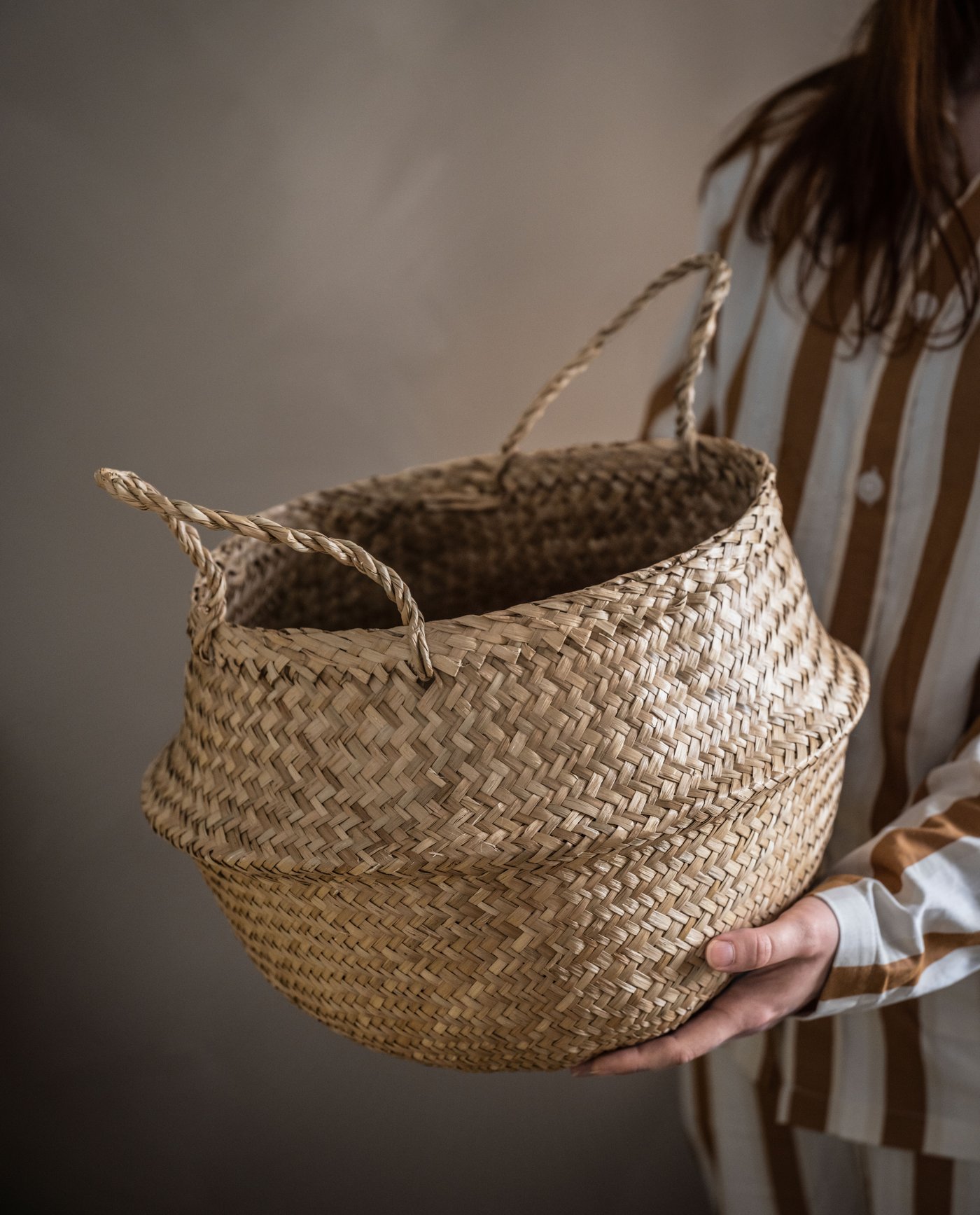 A woman holding a FLÅDIS storage basket.
