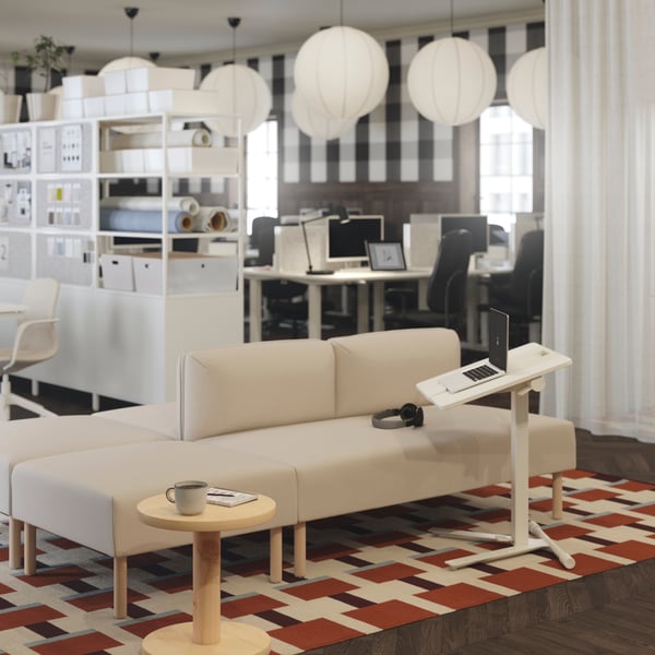 Es ist ein beigefarbenes LILLEHEM Modulsofa mit Holzbeinen und einem weissen MITTZON Laptoptisch zu sehen, der auf einem geometrisch gemusterten Teppich steht.