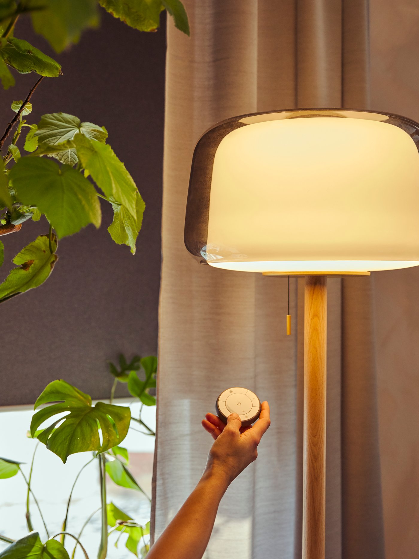 Main tenant une télécommande pour éclairage connecté IKEA. 