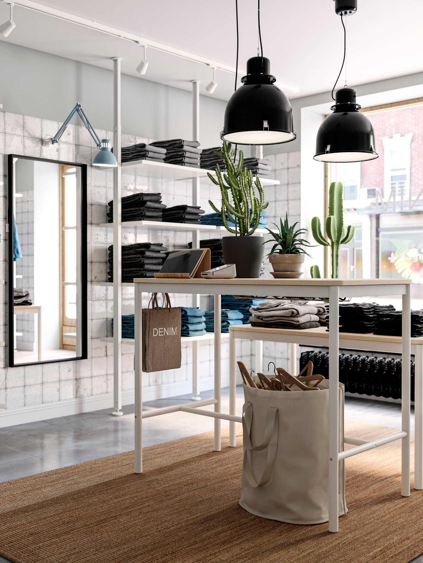 Part of a light denim-store interior with stacks of folded jeans on an ELVARLI storage combination and TOMMARYD tables.