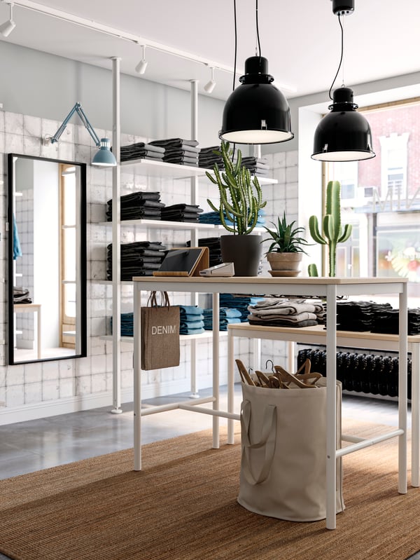 A retail setting with two large hanging lights and a wall shelving unit holding different pairs of folded jeans.