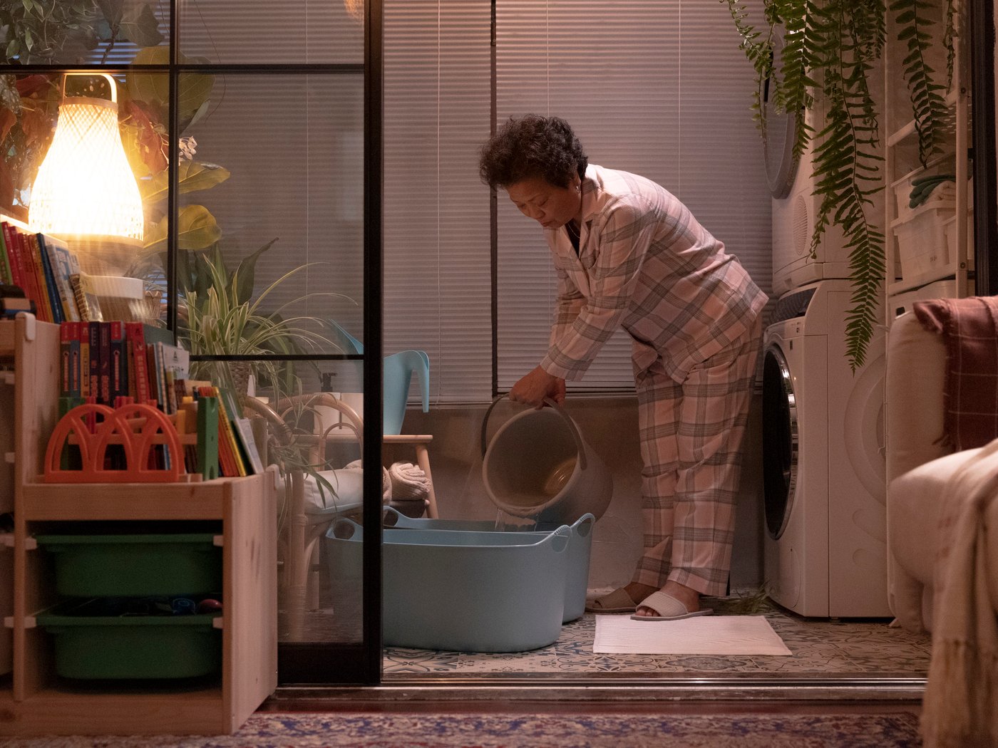 A woman in pyjamas fills up two TORKIS laundry baskets with water.