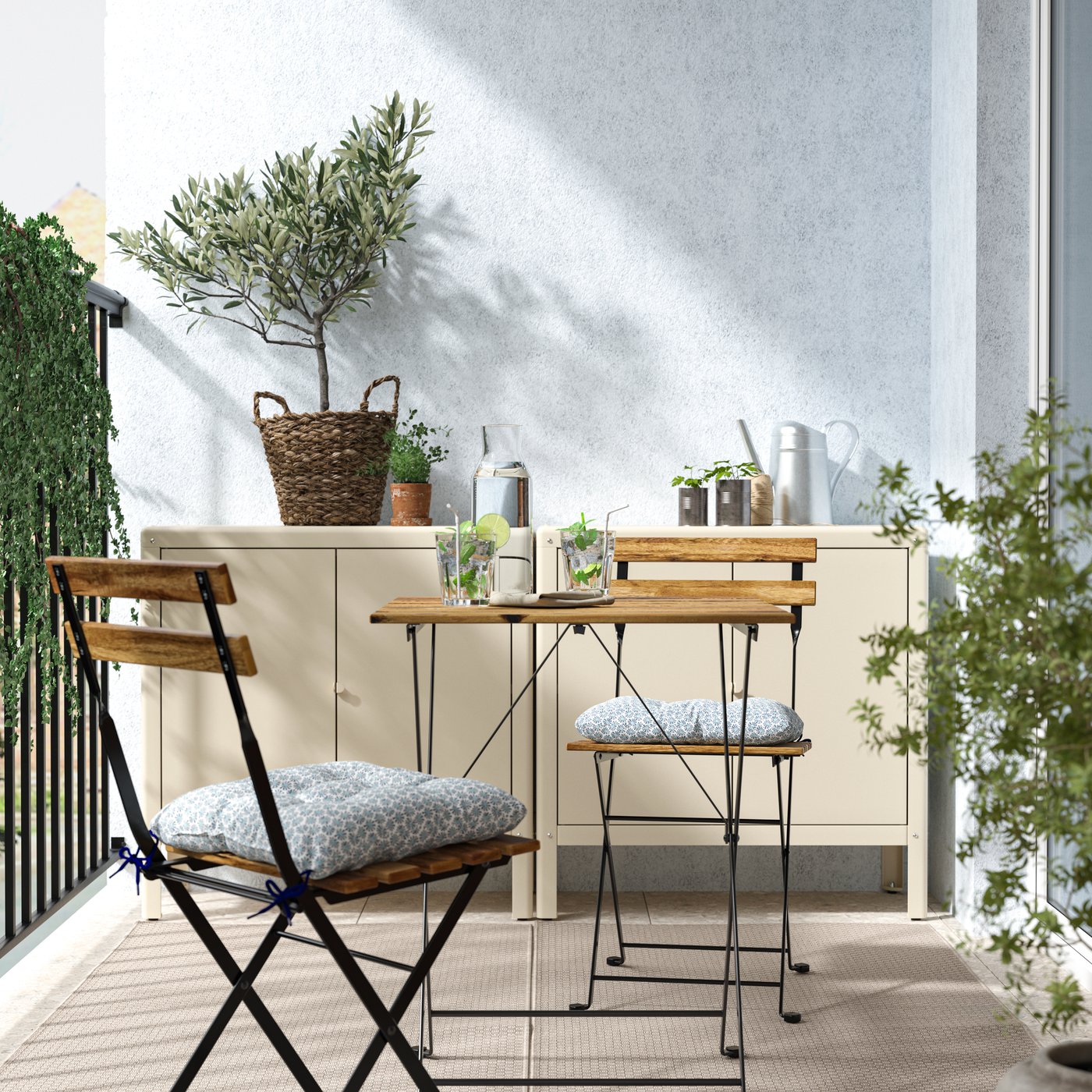 AUn balcón con una mesa y dos sillas plegables TÄRNÖ, detrás de la mesa un mueble organizador con materas con plantas encima.