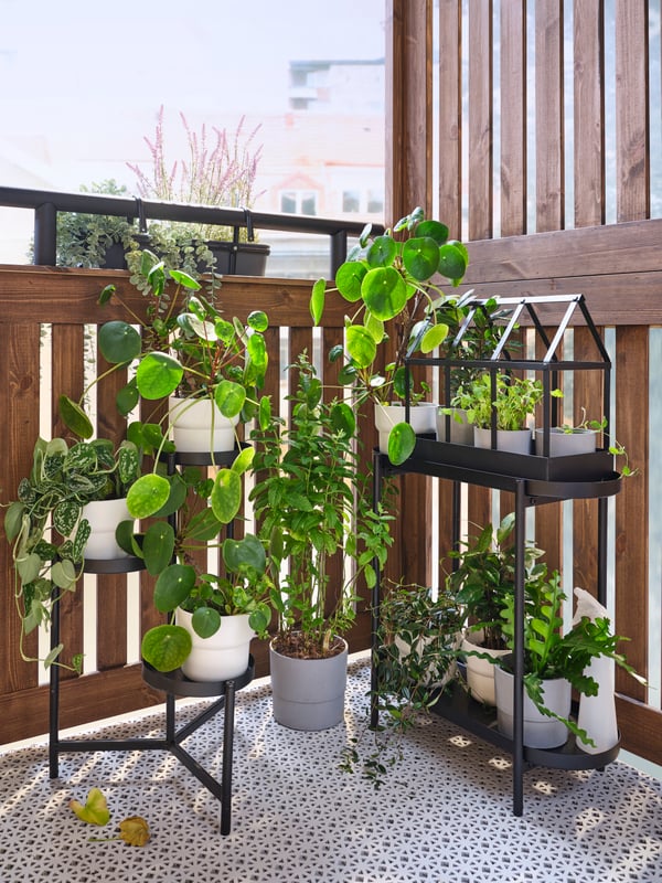 Un balcón pequeño y en su rincón soportes de plantas OLIVBLAD negros con plantas en su interior.