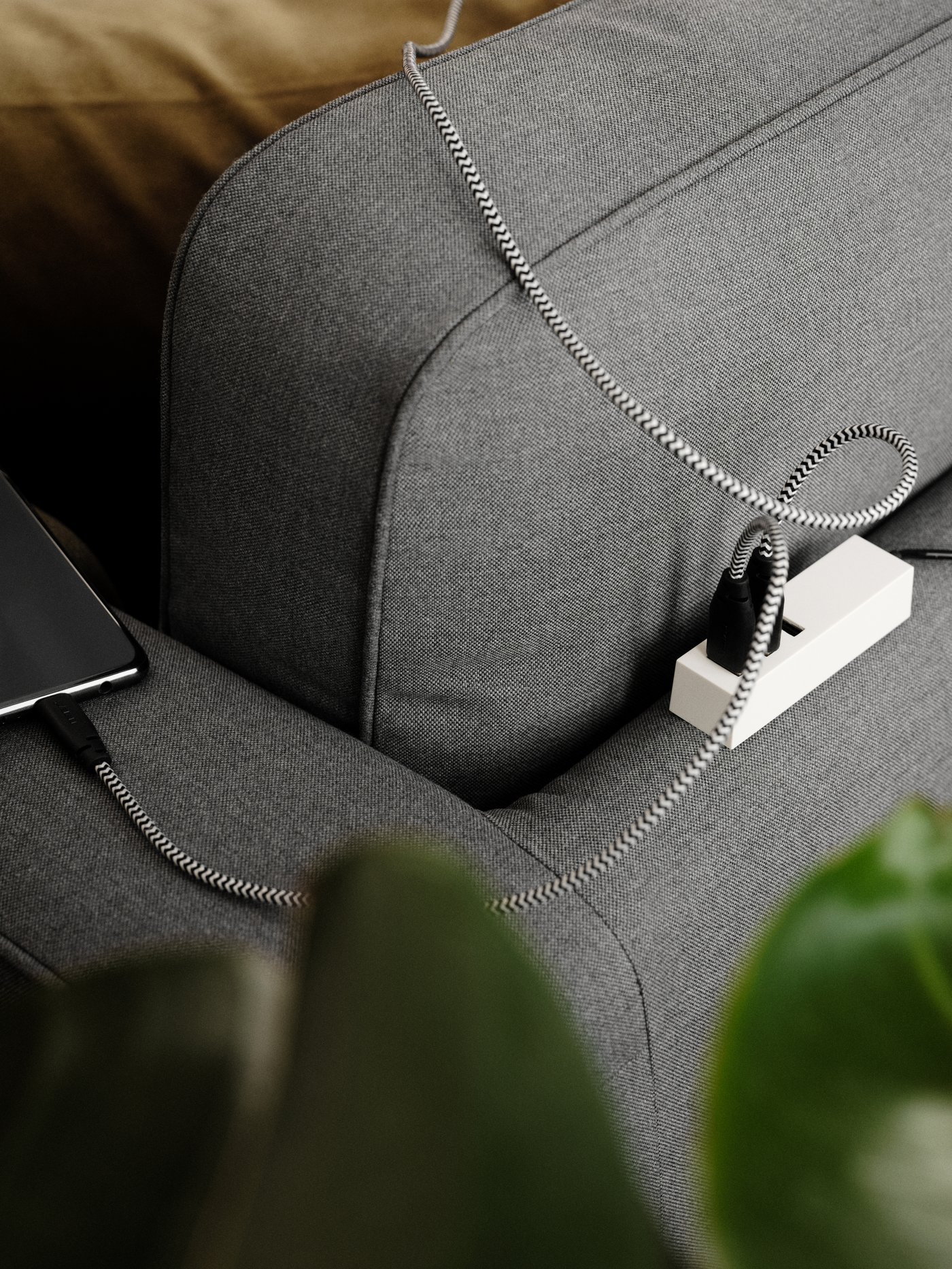 A grey PÄRUP sofa with a charger neatly hidden behind the sofa