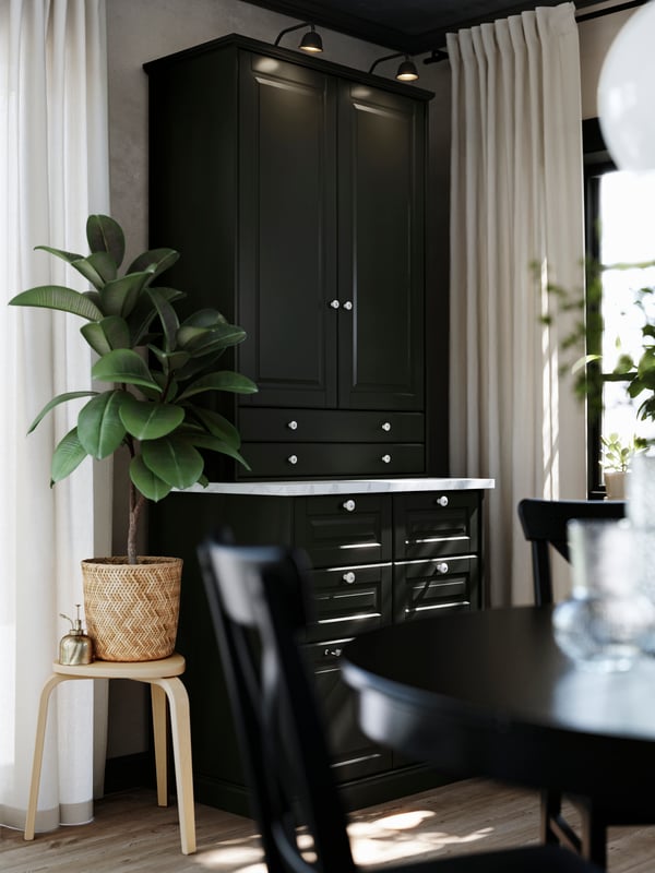 A dining room cabinet, made of METOD kitchen cabinets with traditional black BODBYN fronts, is standing in a dining area.
