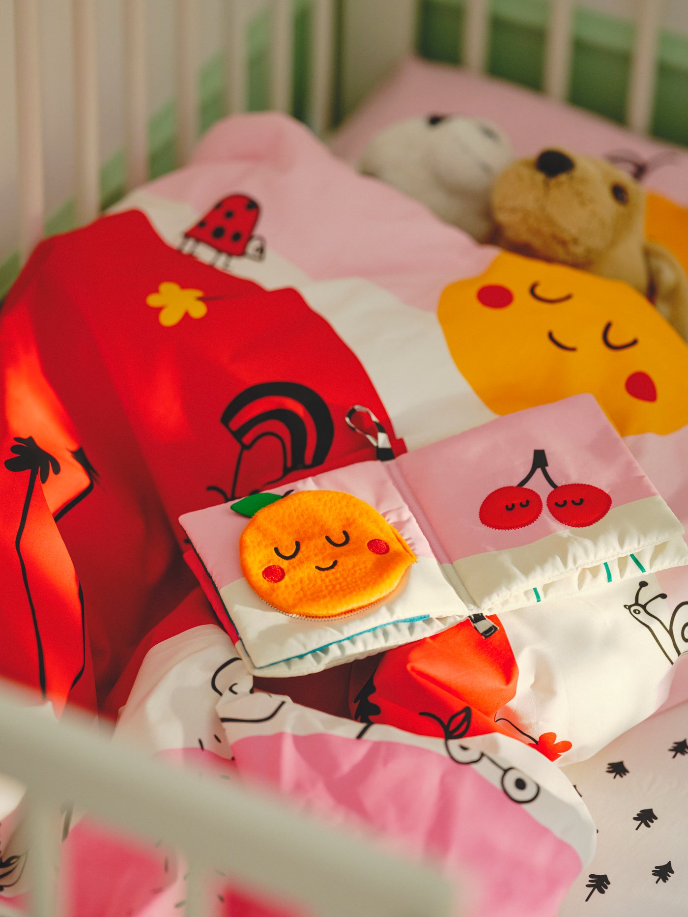 Ein Babybett mit bunter Babybettwäsche.