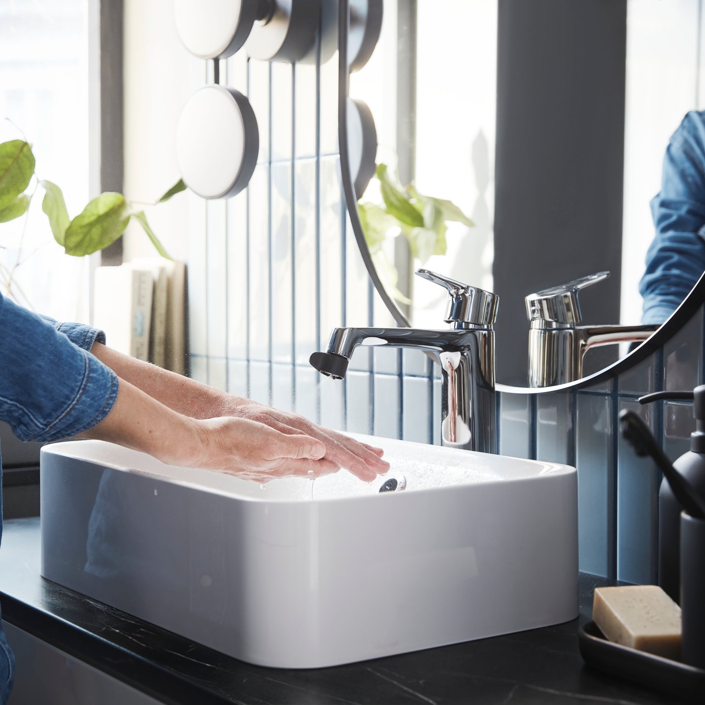 Hands washing in a modern sink fitted with a water-saving ÅBÄCKEN water-saving nozzle.