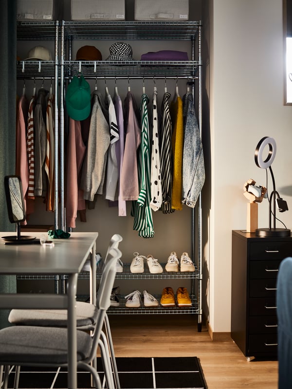 Deux étagères OMAR avec tringle à habits, des vêtements colorés suspendus aux tringles et des baskets sur les tablettes du bas.