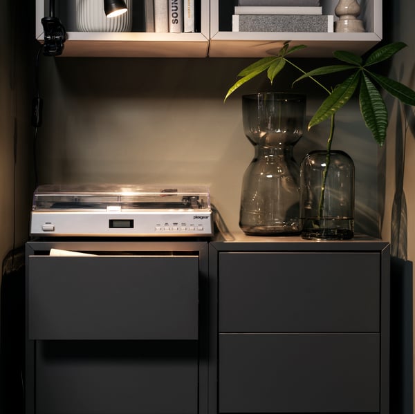 Multiple EKET cabinets, in different colours and types, that together form a column of storage, decoration and empty space.