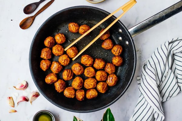 Versare in una delle padelle le polpette a base di proteine vegetali HUVUDROLL congelate e rosolarle su tutti i lati a fuoco basso o moderato per circa 10 minuti