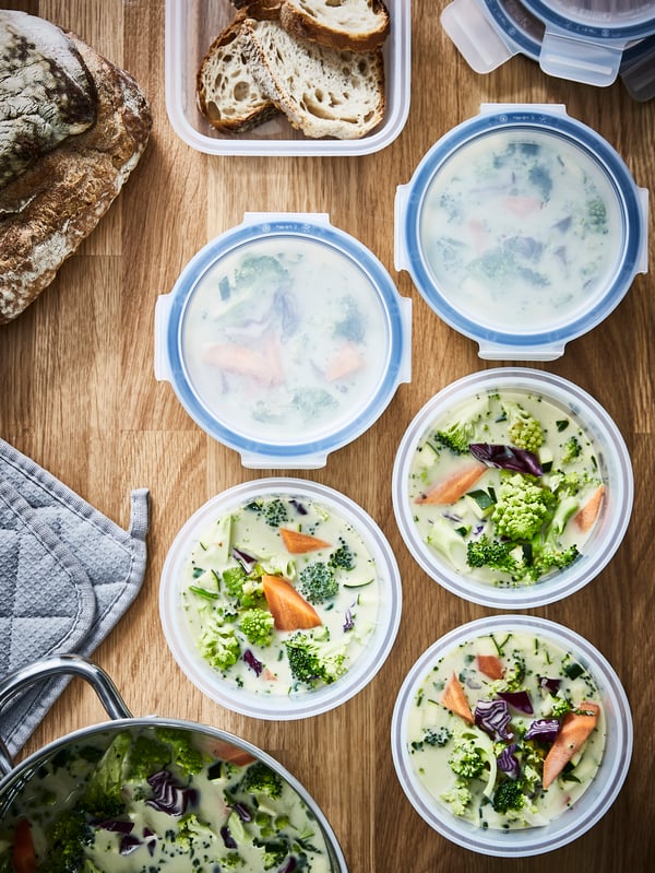 Several round IKEA 365+ food containers, some with lids and some without, have portions of vegetable soup stored inside.