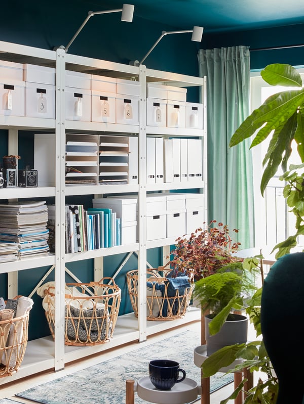 BROR shelving unit with storage boxes, cameras, magazines, books, magazine files and three baskets in rattan.