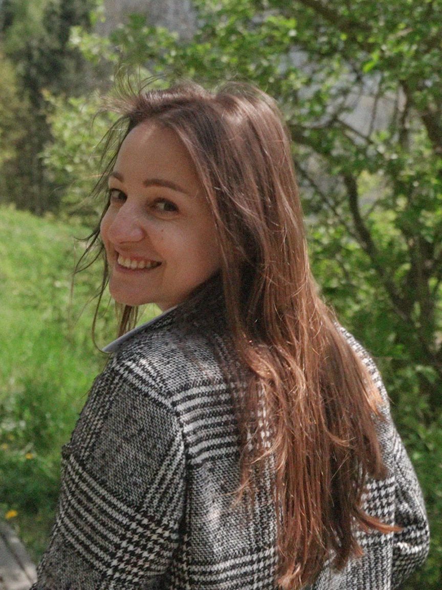 Nataliia, med ett stort leende på läpparna, går längs en pittoresk stig omgiven av lummig grönska.