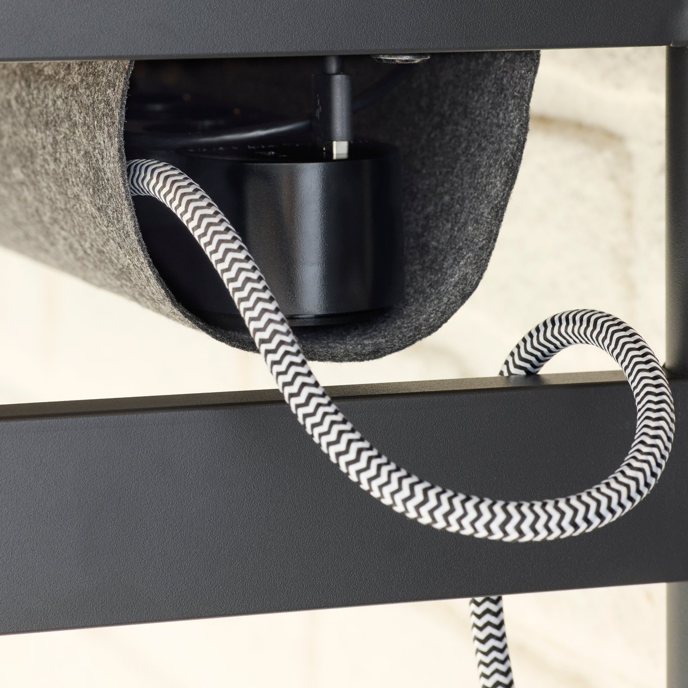 Gros plan sur un câble USB et sur le range-câbles équipant la face inférieure du plateau d’un bureau MULLSJÖ.