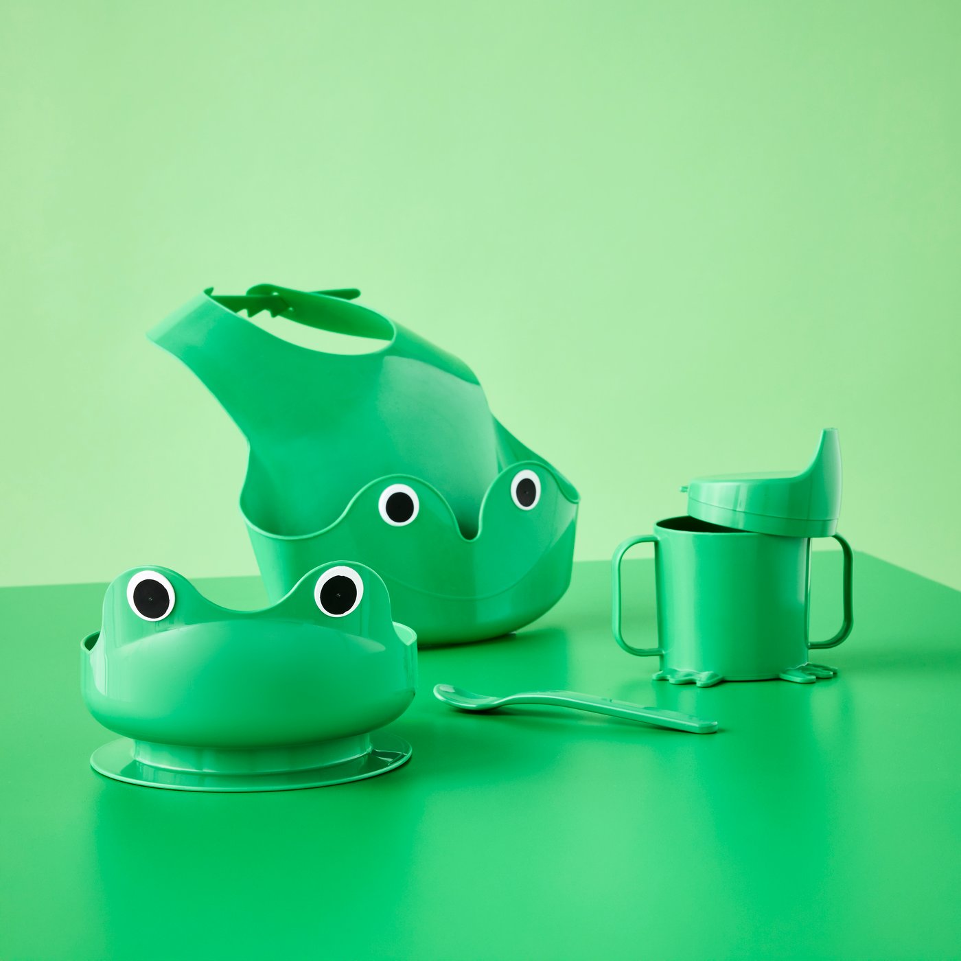Bright green frog-themed four-piece MATA baby tableware set with bib, bowl, sippy cup and spoon.