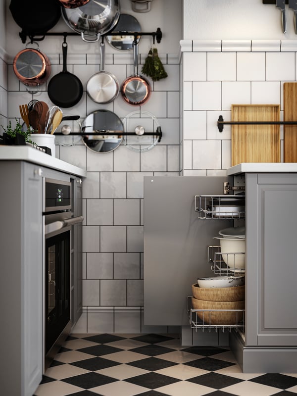A base cabinet with the door open and mesh baskets drawn out next to a hob and oven in a kitchen with grey BODBYN fronts.