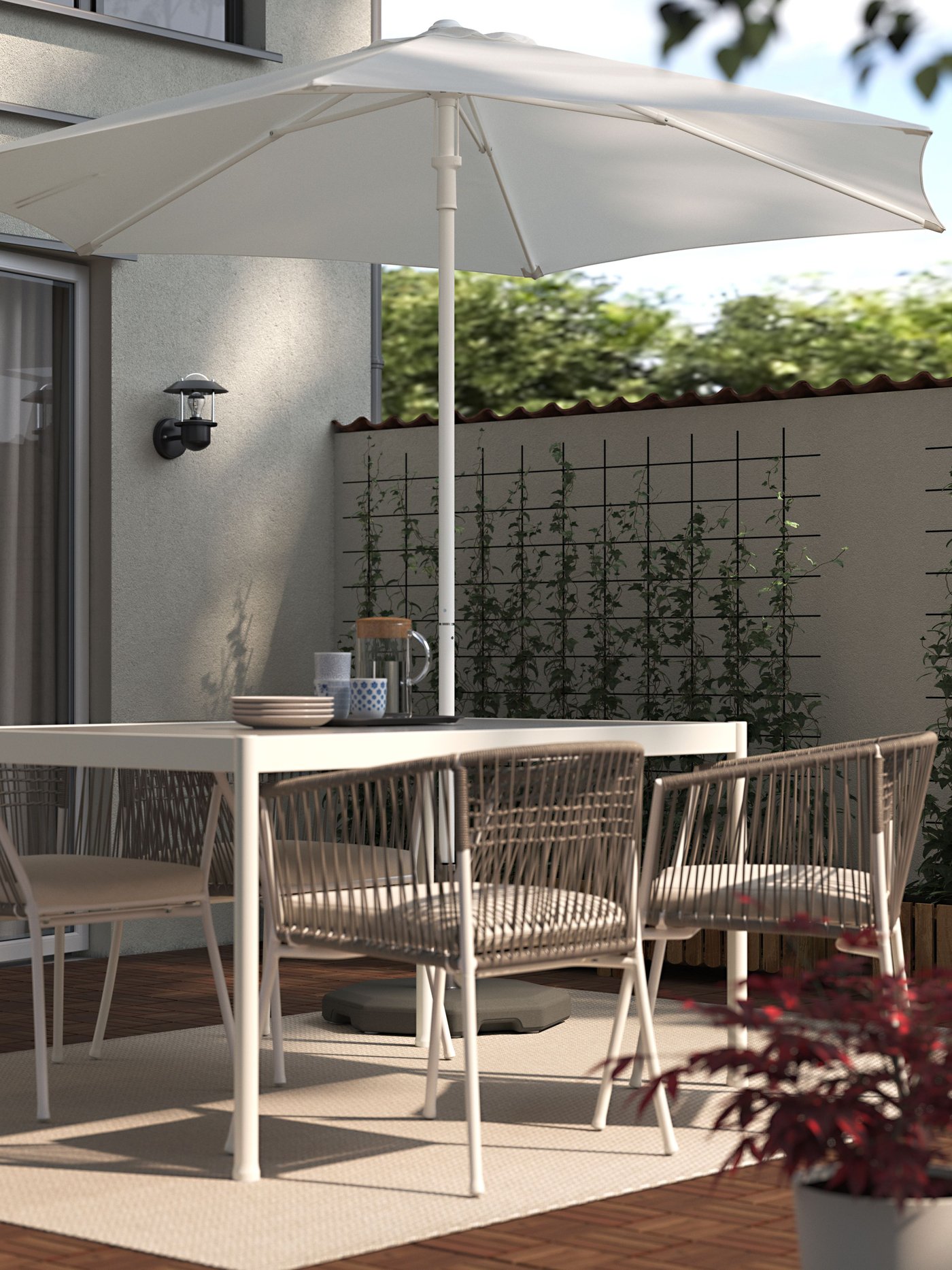 Una mesa de terraza SEGERÖN sobre una alfombra de terraza con un quitasol encima.
