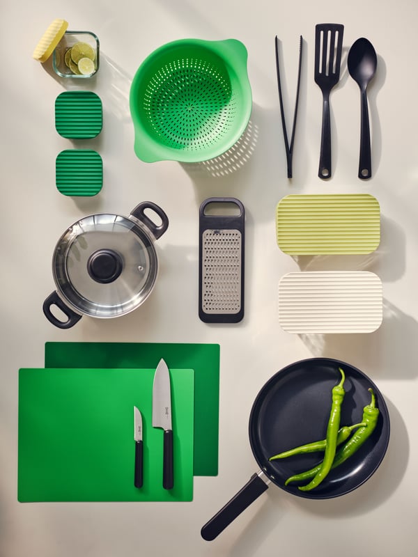 College kitchen starter kit for students with bright green chopping board and cullender, saucepan, frying pan and utensils.