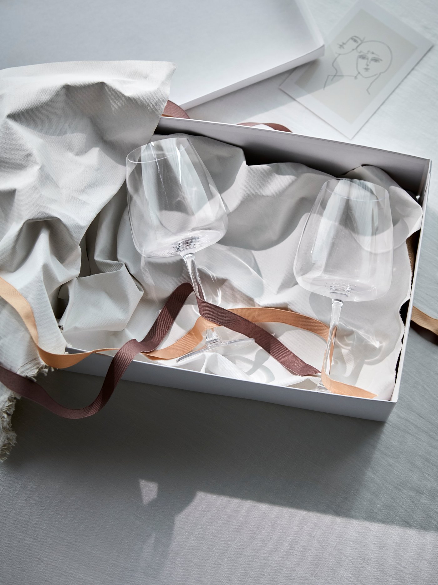 A white wedding cards or keepsake box on a white surface with ribbons.