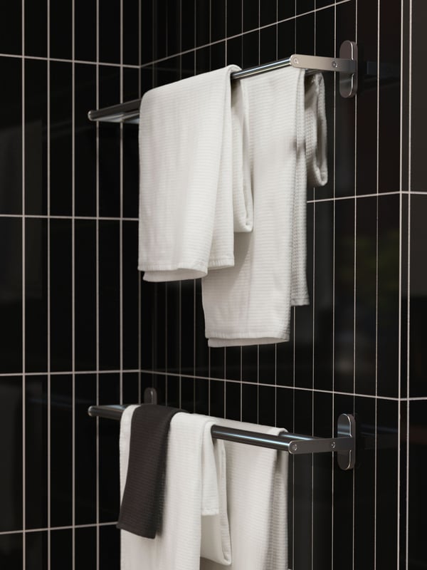 Two BROGRUND towel rails are mounted on a black-tiled bathroom wall. Four neatly folded white towels are hanging from them.